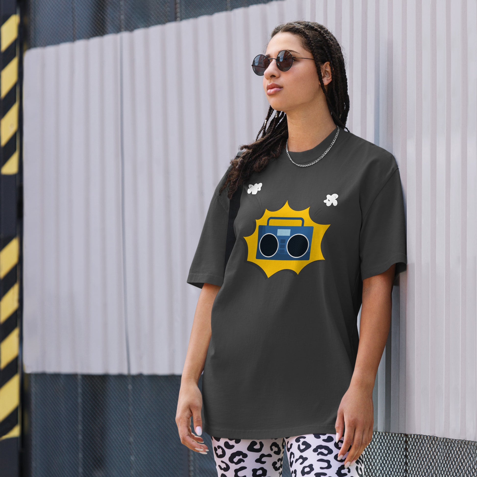 Woman in a faded black oversized tee with a vibrant yellow retro mixtape graphic, combining classic style with a punch of personality for any casual occasion.