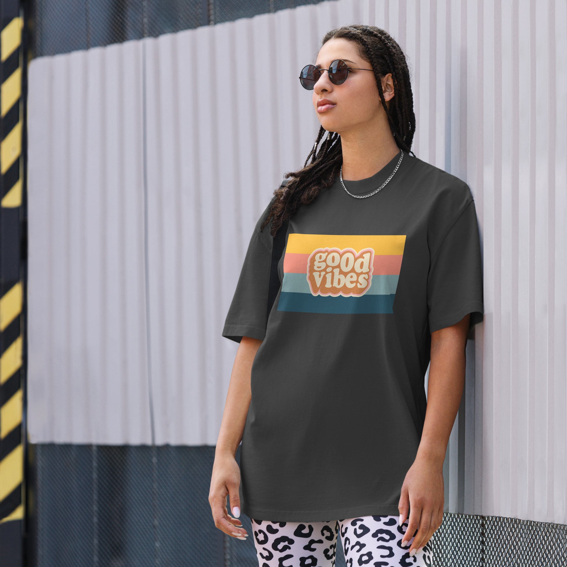 Woman in a trendy graphic faded black tee with a retro sunset design that reads 'good vibes', exuding a casual, cool attitude.