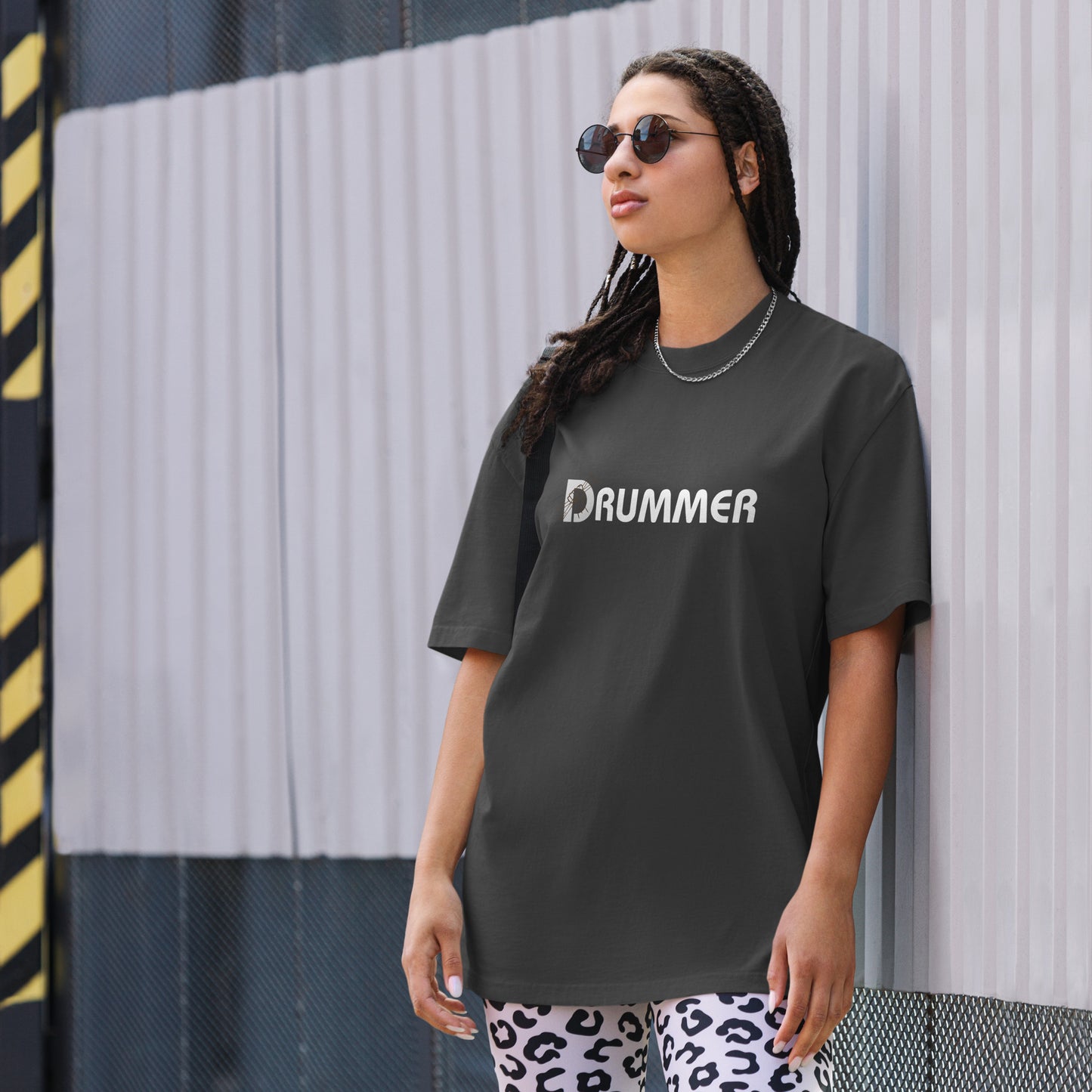 Fashion-forward woman in a minimalist faded black 'DRUMMER' print t-shirt, exuding confidence.