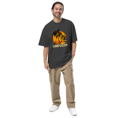 Cheerful man in Men's "Tropical Simplicity" Vintage faded black Oversized Tee featuring a palm tree silhouette against an orange backdrop, capturing the essence of relaxed style