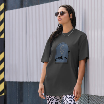 Woman wearing a faded black oversized faded tee with a dreamy mountain night design, showcasing unique self-expression and bold fashion.