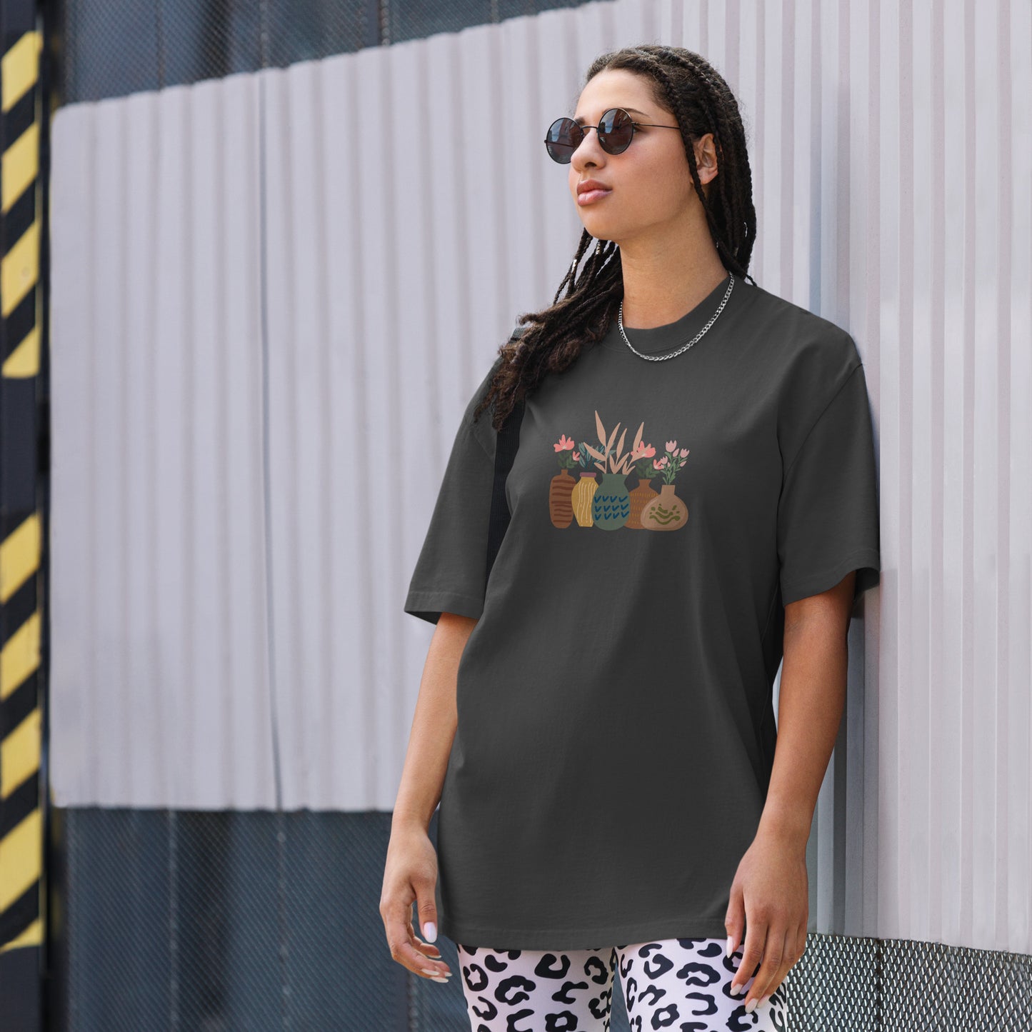 Woman wearing a faded black oversized faded tee with an eclectic potted plants design, highlighting unique self-expression and vibrant fashion.