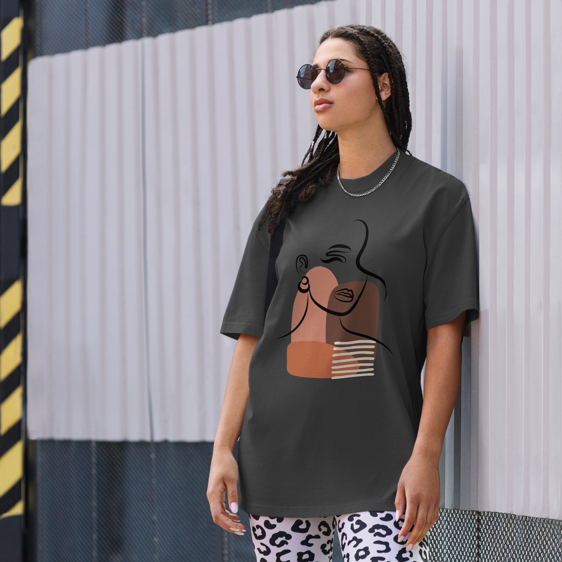 Woman wearing a faded black oversized faded tee with an abstract empowered woman design, highlighting unique self-expression and bold artistic fashion. 