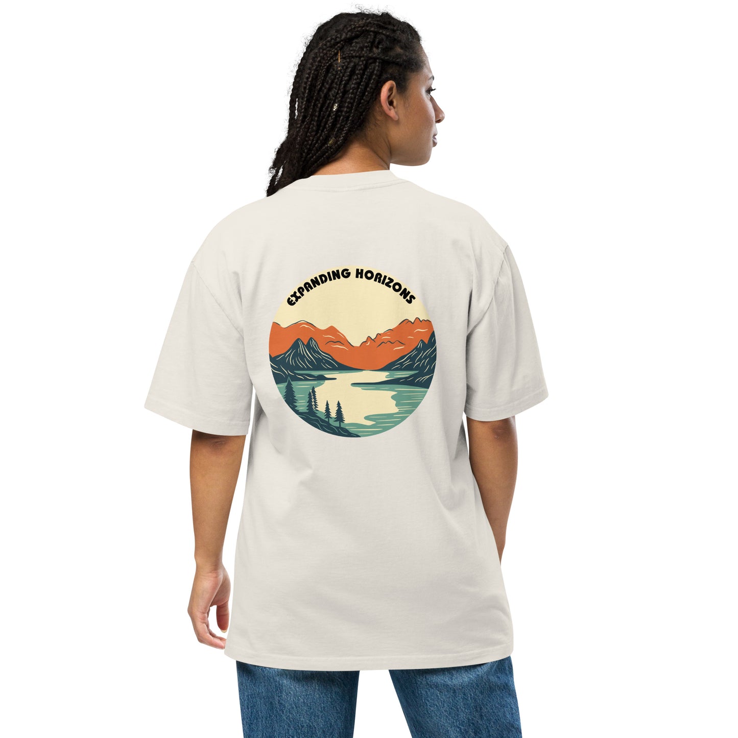 Woman wearing a faded bone 'Expanding Horizons' Oversized Tee from Be You Out Loud, showcasing a scenic mountain and lake graphic in warm hues, signifying adventure and tranquility.