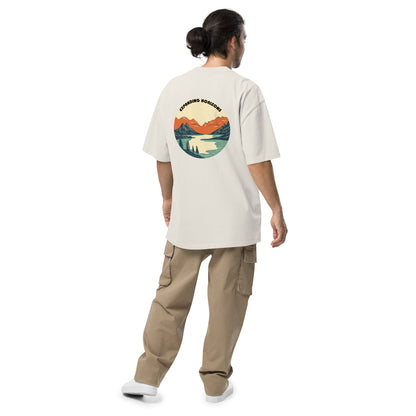 Man from behind wearing Be You Out Loud Men's "Expanding Horizons" faded bone Oversized Tee, featuring a retro mountain lake design, promoting exploration and self-expression.