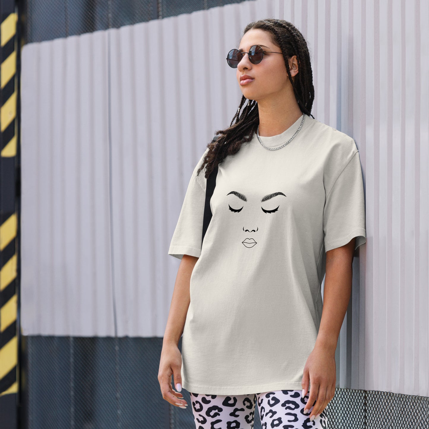 Woman in a chic, minimalist 'Artistic Expression' faded bone Oversized Tee, adorned with a stylized facial outline, exuding a love for simplicity and art, with diverse color options and sizes S-3XL available.