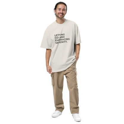 Man wearing a faded bone oversized faded tee in off-white with "Letting Go and Embracing Serenity" text. 