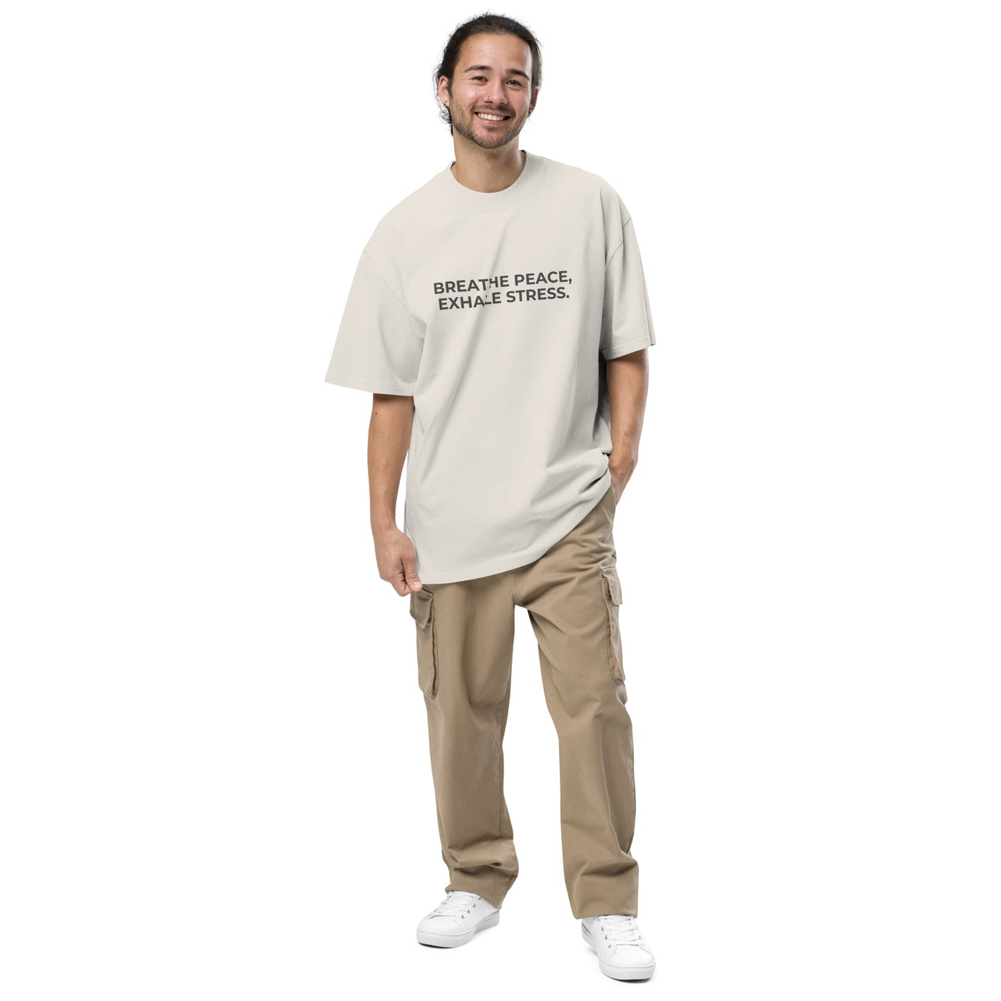 Man wearing a faded bone oversized faded tee in off-white with "Breathe Peace, Exhale Stress" text. 