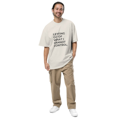 Man wearing a faded bone oversized faded tee in light beige with "Letting Go of What I Cannot Control" text.