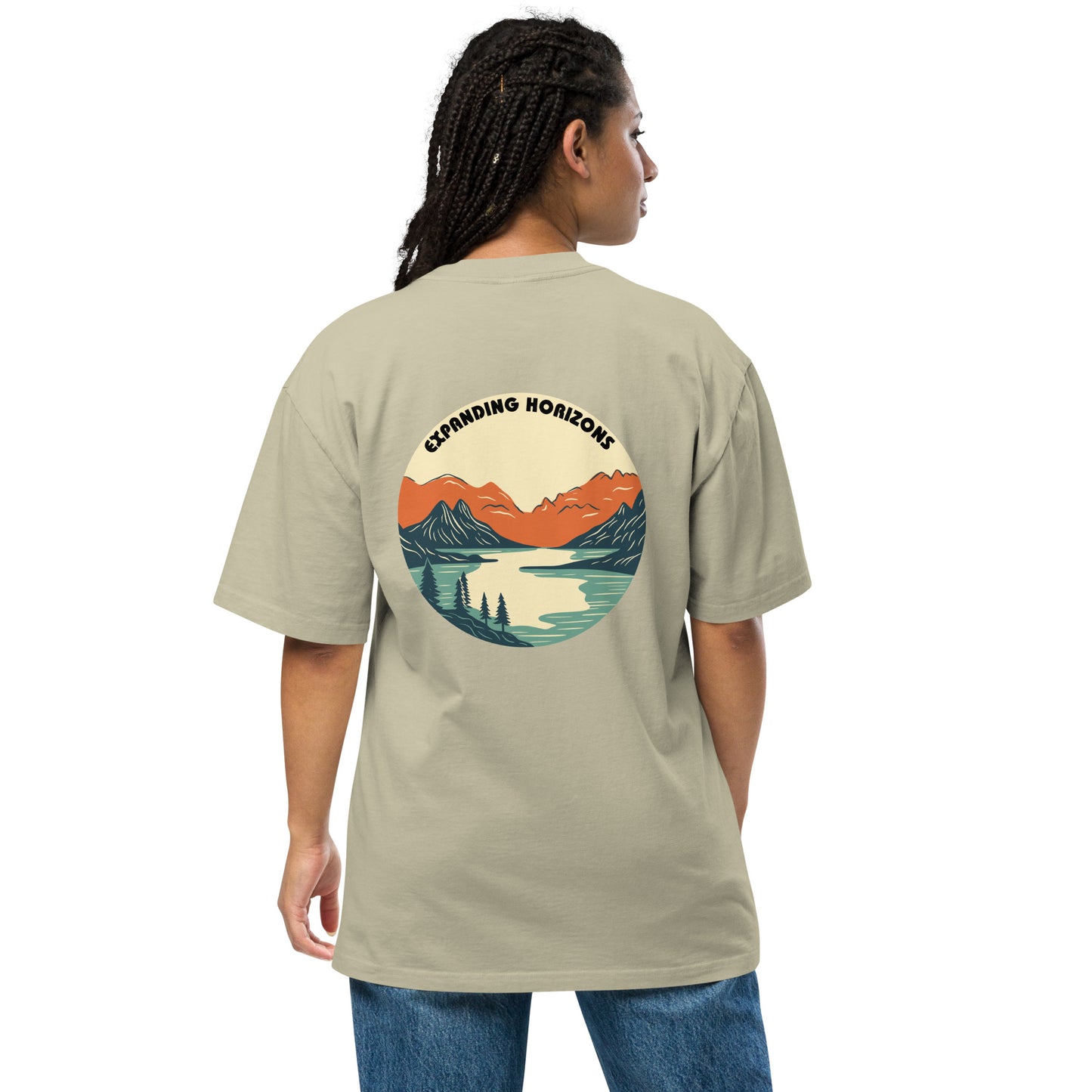 Woman wearing a faded eucalyptus 'Expanding Horizons' Oversized Tee from Be You Out Loud, showcasing a scenic mountain and lake graphic in warm hues, signifying adventure and tranquility.