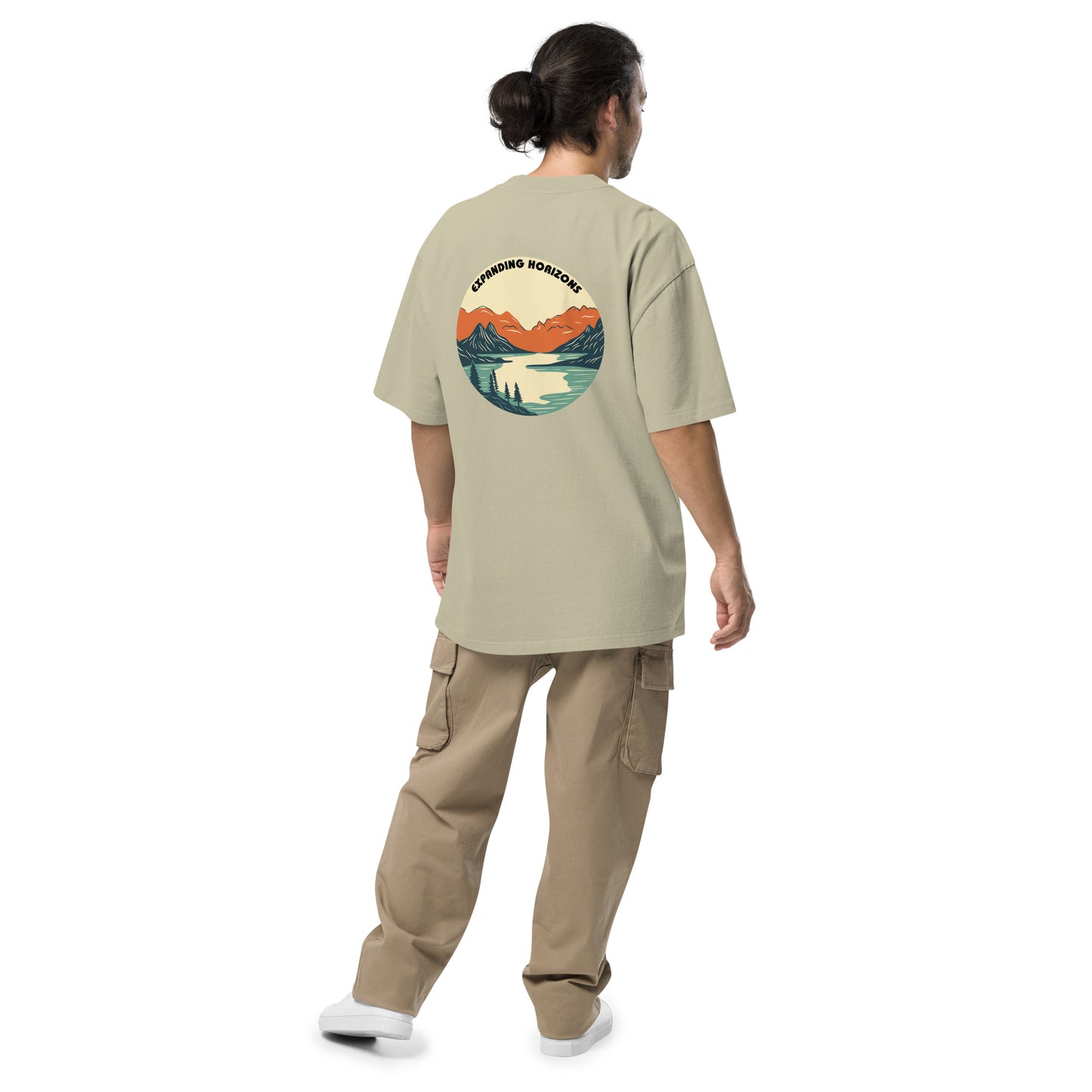 Man from behind wearing Be You Out Loud Men's "Expanding Horizons" faded eucalyptus Oversized Tee, featuring a retro mountain lake design, promoting exploration and self-expression.