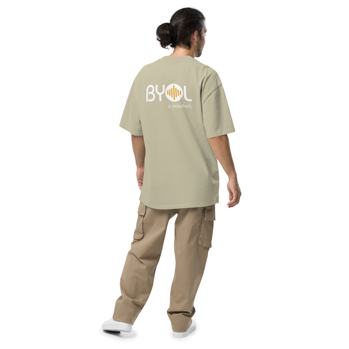 A young man with long hair in a ponytail wearing a faded uecalyptus "BYOL: a mindset" T-shirt, viewed from the back. The T-shirt features the "BYOL" logo on the back and is available in multiple colors (dark gray, beige, light blue) and sizes (S-3XL). The "be you out loud" logo is displayed at the top.