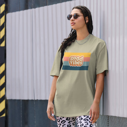 Woman in a trendy graphic faded eucalyptus tee with a retro sunset design that reads 'good vibes', exuding a casual, cool attitude.