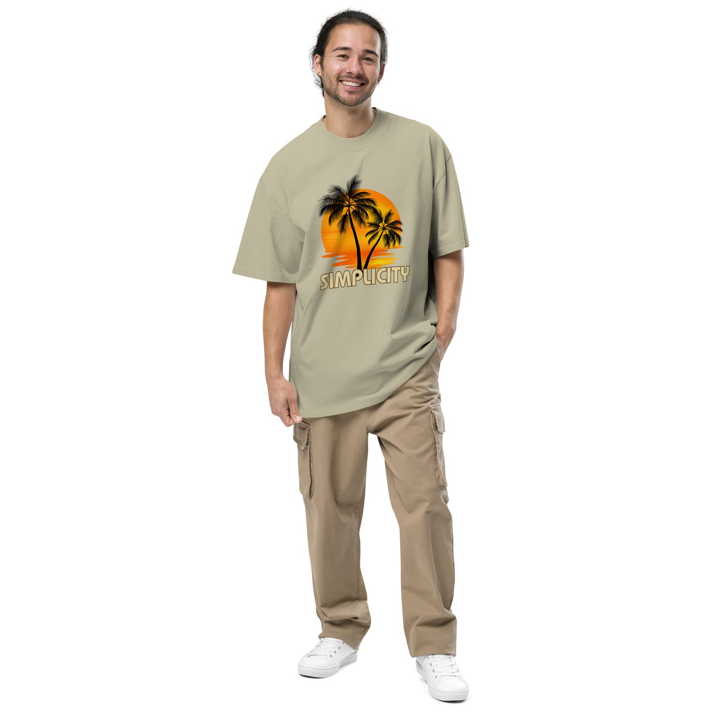 Cheerful man in Men's "Tropical Simplicity" Vintage faded eucalyptus Oversized Tee featuring a palm tree silhouette against an orange backdrop, capturing the essence of relaxed style