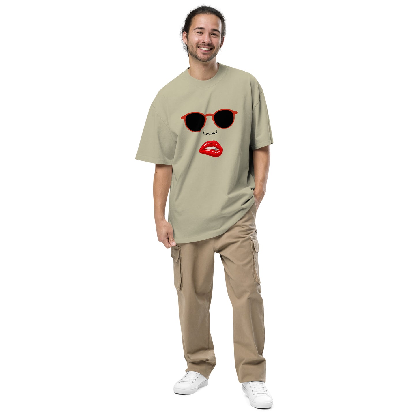 Smiling man wearing Men's Oversized Tee in faded eucalyptus, adorned with a pop art design featuring red lips and red sunglasses, offering a bold fashion statement