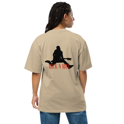 Woman facing away, wearing a Be You Out Loud faded khaki oversized tee with a "Rock N Roll" silhouette design, exuding a vintage yet edgy style