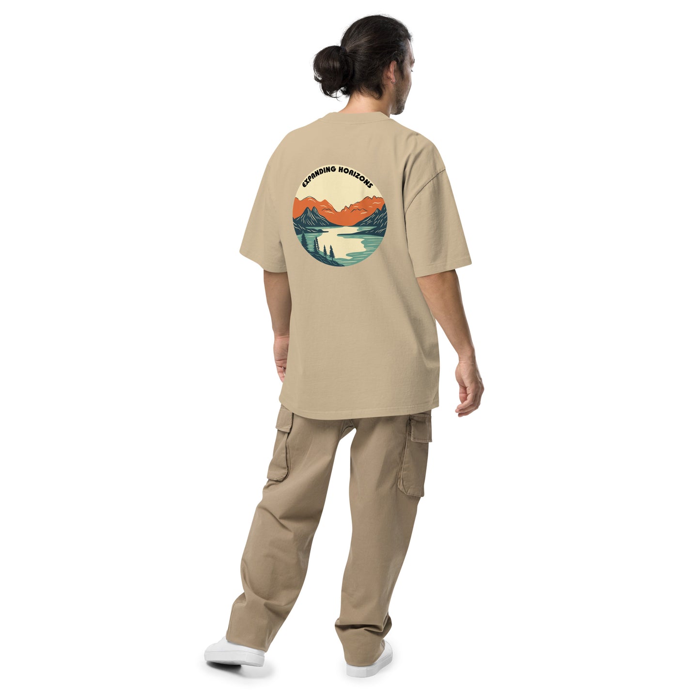 Man from behind wearing Be You Out Loud Men's "Expanding Horizons" faded khaki Oversized Tee, featuring a retro mountain lake design, promoting exploration and self-expression.