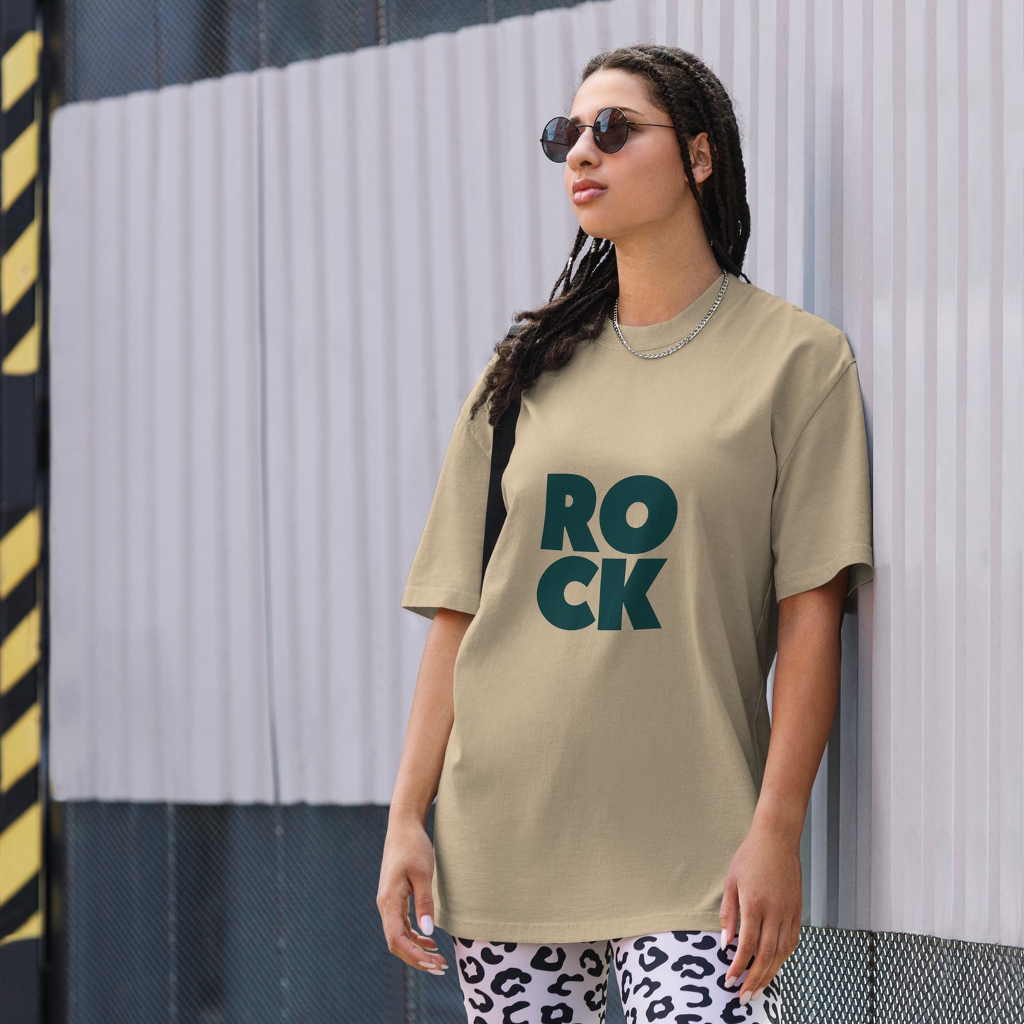 Confident individual rocking a bold faded khaki oversized graphic tee with an oversized, faded ROCK design, embodying fearless self-expression.