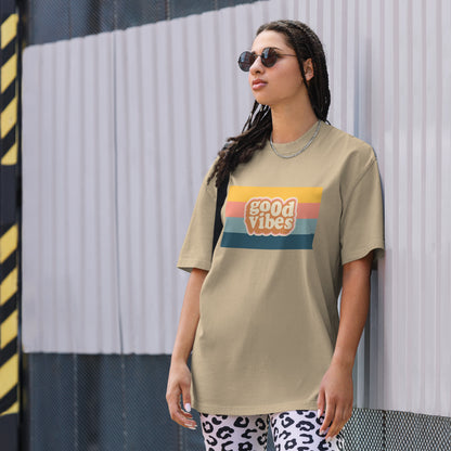 Woman in a trendy graphic faded khaki tee with a retro sunset design that reads 'good vibes', exuding a casual, cool attitude.