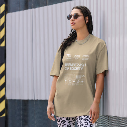 A woman models a Women's 'Member-ish of Society' faded khaki Oversized Tee, featuring a humorous, nutrition-fact-style graphic. Tee is paired with a subtle chain necklace and cool sunglasses, adding a touch of irony to casual wear. 