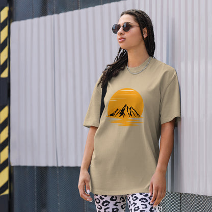 Fashion-forward woman in a Women's Sunset Mountains Lifestyle faded khaki Oversized Tee against an urban backdrop, echoing the adventure of Be You Out Loud.