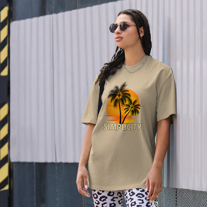 A woman in a Women's Sunset Simplicity faded khaki Oversized Tee with a minimalist palm design in soft earth tones, exuding calm and trendy vibes.