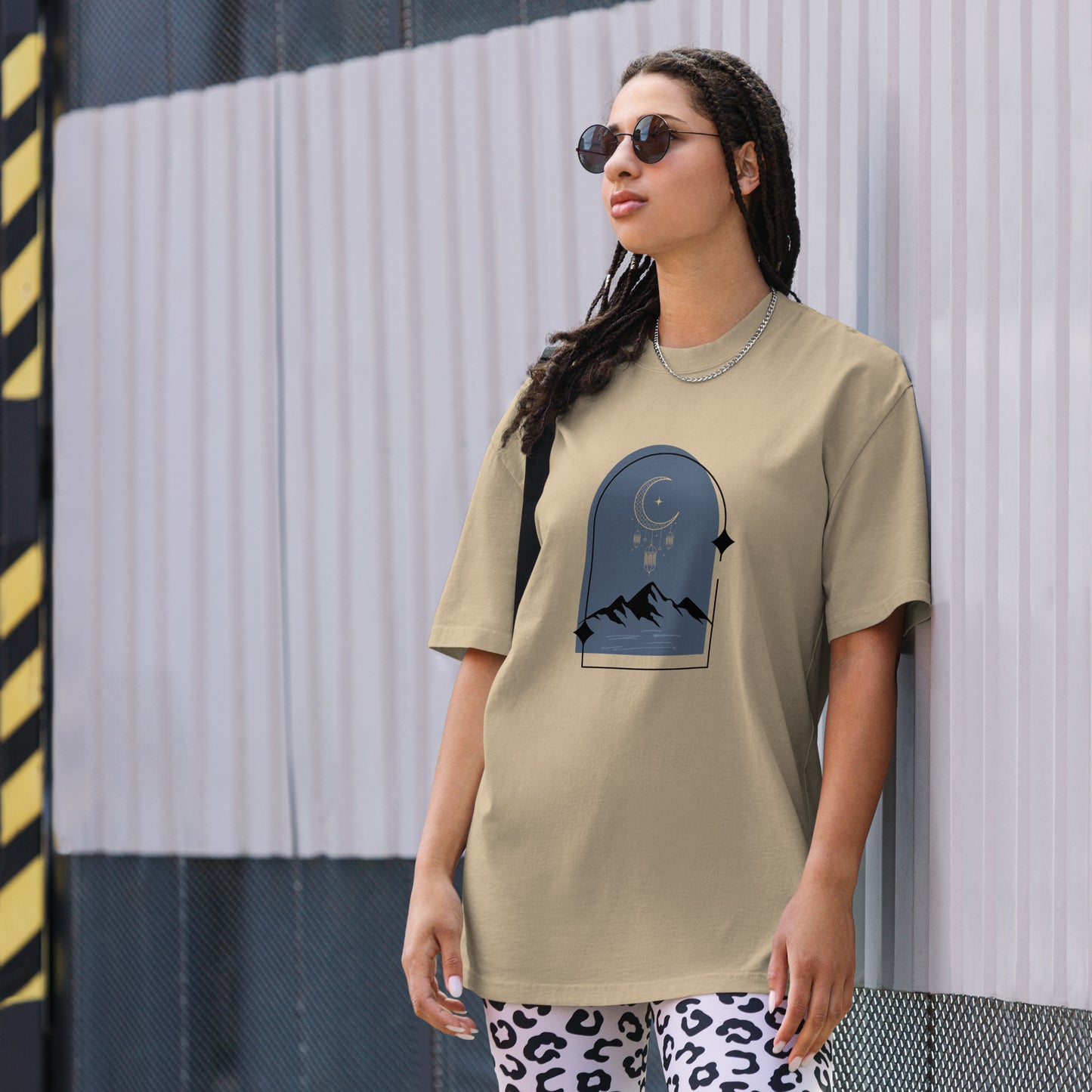 Woman wearing a faded khaki oversized faded tee with a dreamy mountain night design, showcasing unique self-expression and bold fashion.