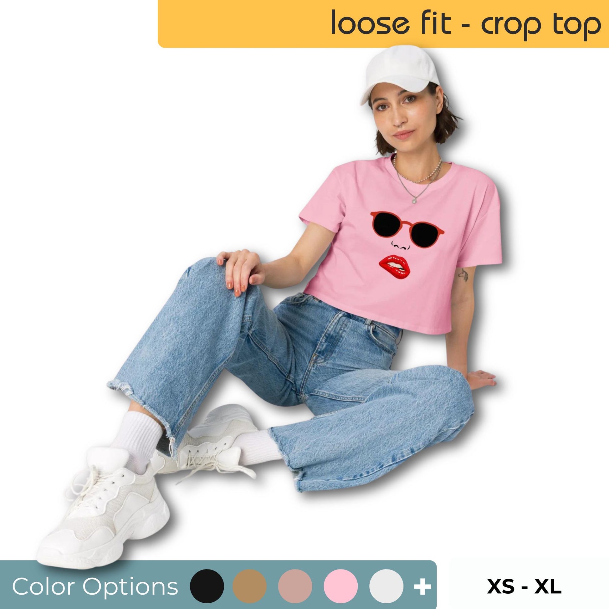 Woman seated wearing a pink loose-fit crop top with a red lip and black shades graphic, displayed with size and color options.