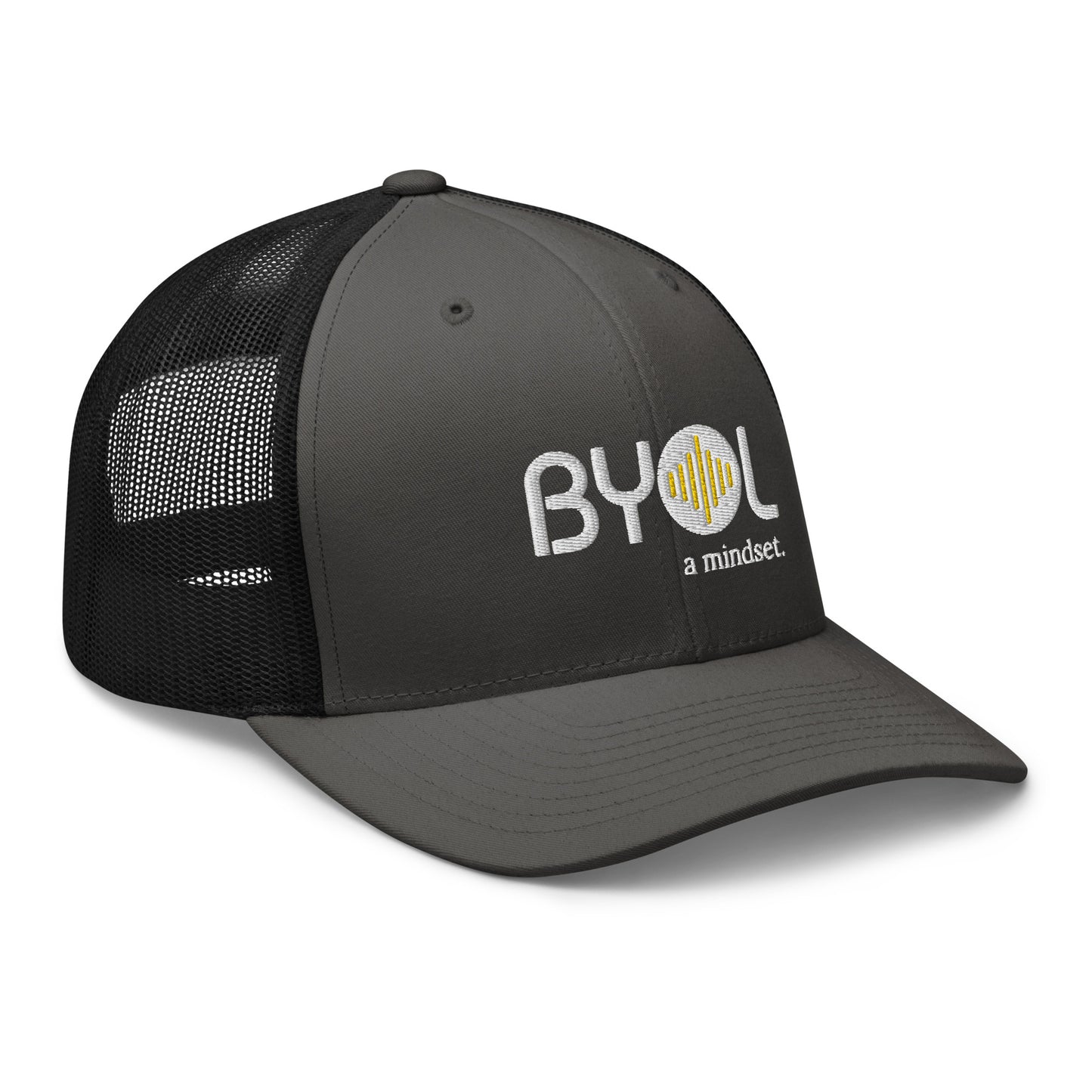 Dark grey and black retro trucker hat with "BYOL a mindset" embroidered on the front in white and yellow, displayed against a clean background. Available in various colors: black, white, brown, green, and beige.