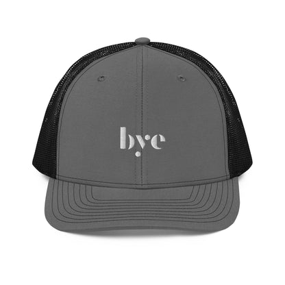 A structured grey and black trucker cap mesh back. The front features a white embroidered logo that reads "b.y.e" in lowercase letters. The cap has a curved brim with stitching detail and an adjustable snapback closure at the rear.