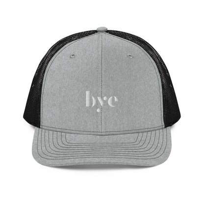 A structured grey and black trucker cap mesh back. The front features a white embroidered logo that reads "b.y.e" in lowercase letters. The cap has a curved brim with stitching detail and an adjustable snapback closure at the rear.