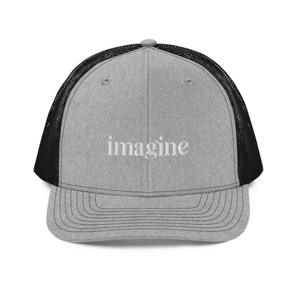 A grey and black snapback trucker cap with the word "imagine" embroidered in white cursive letters on the front panel. The hat features a curved visor, structured front panels, and breathable mesh on the sides and back, with an adjustable snap closure for a comfortable, customized fit.