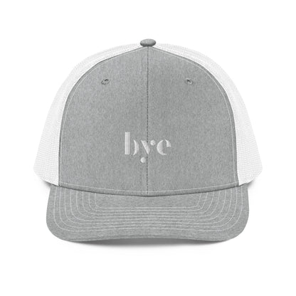 A structured light grey and white trucker cap mesh back. The front features a white embroidered logo that reads "b.y.e" in lowercase letters. The cap has a curved brim with stitching detail and an adjustable snapback closure at the rear.