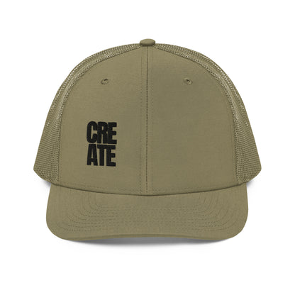 A military green snapback trucker cap with the word "CREATE" in bold black letters divided across the front panel. It features a pre-curved visor, a structured front crown, black mesh back panels for breathability, and an adjustable snap closure to fit various head sizes comfortably.