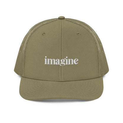 A military green snapback trucker cap with the word "imagine" embroidered in white cursive letters on the front panel. The hat features a curved visor, structured front panels, and breathable mesh on the sides and back, with an adjustable snap closure for a comfortable, customized fit.