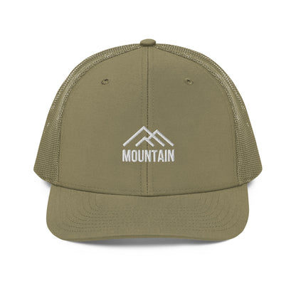 An military green snapback trucker cap with a stylized white mountain range emblem above the word "MOUNTAIN," also in white, embroidered on the front panel. This cap features a curved visor, a structured front crown, mesh side and back panels for ventilation, and an adjustable snapback closure for a tailored fit.