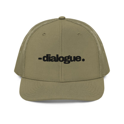 A military green snapback trucker cap with the word "-dialogue." in black, modern font, centered on the front panel. The cap is designed with a curved brim, white mesh back panels for breathability, and an adjustable snap closure for a customizable fit.