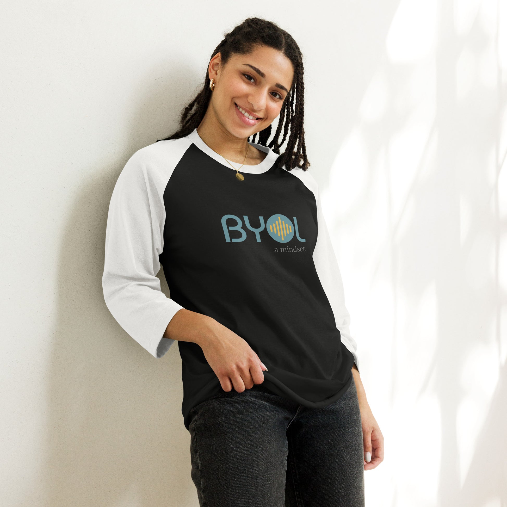 Woman wearing a black and white BYOL mindset raglan t-shirt with color options in red, black, gray, and green, available in sizes S to 3XL.