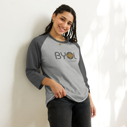 Woman wearing a light gray and dark grey BYOL mindset raglan t-shirt with color options in red, black, white, and green, available in sizes S to 3XL.