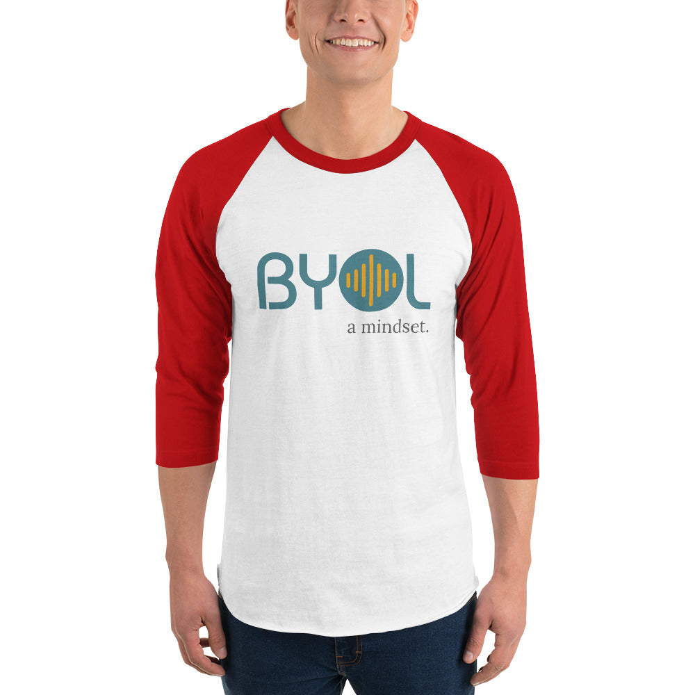 A young man wearing a white and red "BYOL: a mindset" raglan T-shirt with three-quarter sleeves, smiling and standing with his arms at his sides. The T-shirt features the "BYOL" logo in teal and yellow on the front and is available in multiple colors (red, black, white, green, plus more) and sizes (S-3XL). The "be you out loud" logo is displayed at the top.