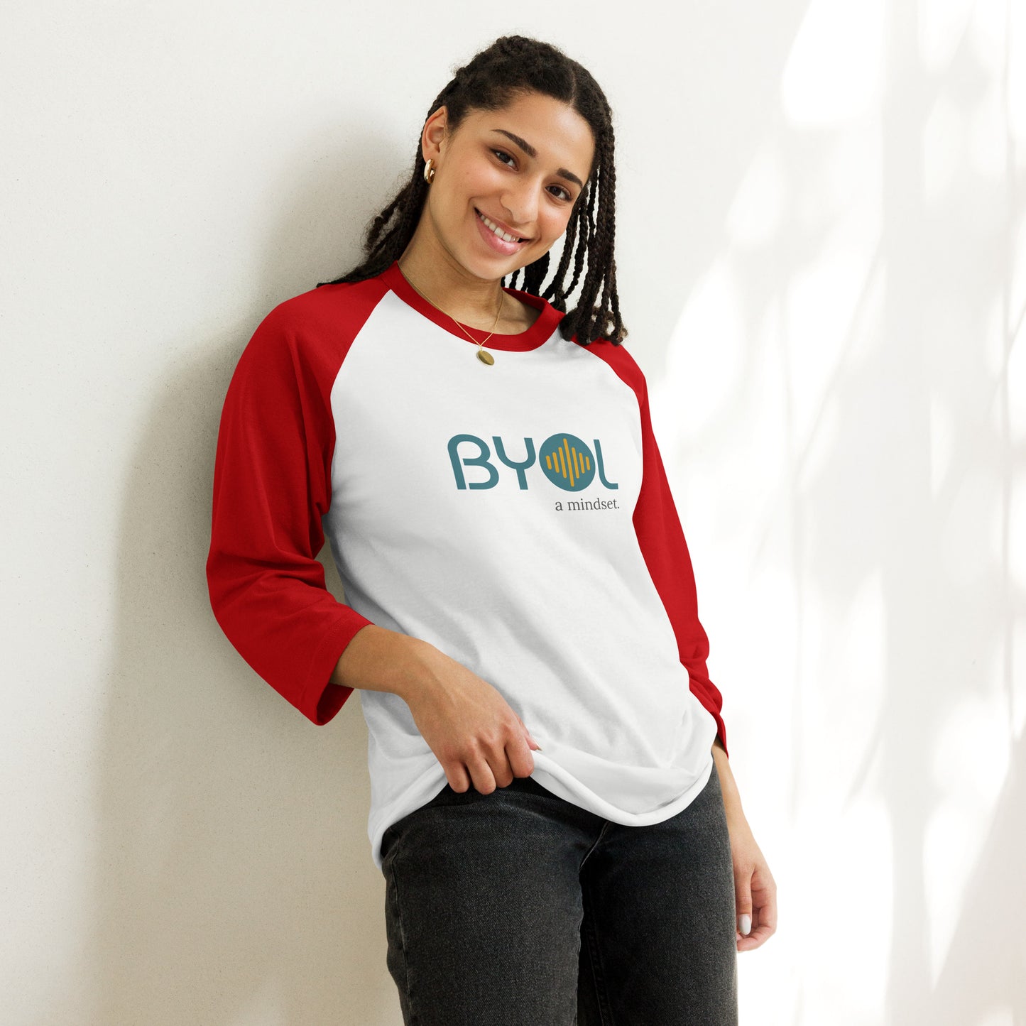 Woman wearing a white and red BYOL mindset raglan t-shirt with color options in red, black, gray, and green, available in sizes S to 3XL.