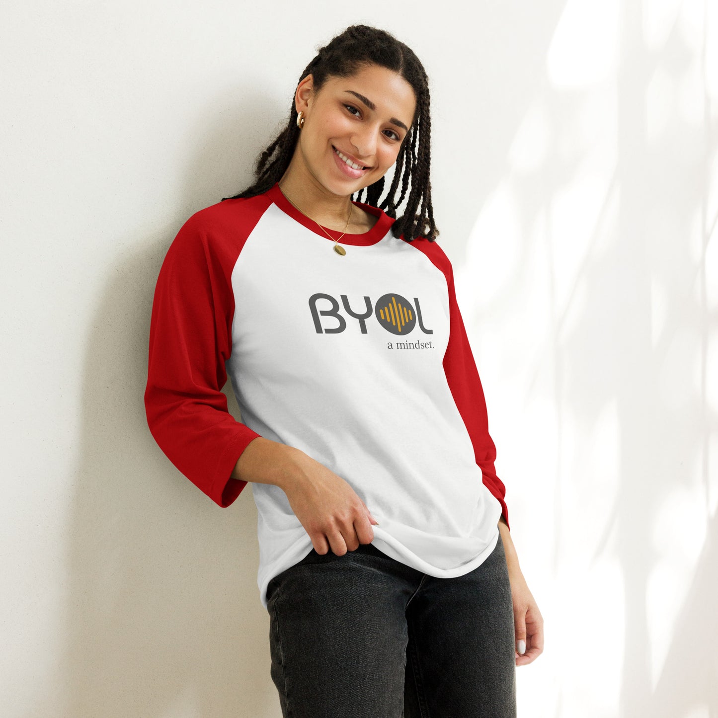 Woman wearing a white and red BYOL mindset raglan t-shirt with color options in red, black, white, and green, available in sizes S to 3XL.