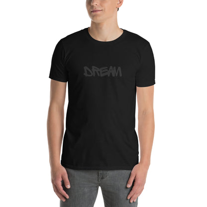 A young man is wearing a black t-shirt with the word "DREAM" written in a freehand, black font across the chest, conveying a message of hope and ambition.