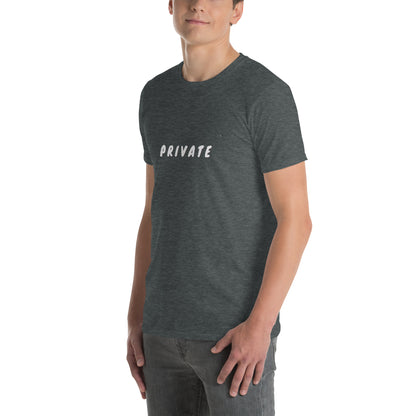 A man is wearing a charcoal grey t-shirt with the word "PRIVATE" printed across the chest in white capital letters, standing casually with one hand partially in his pocket.