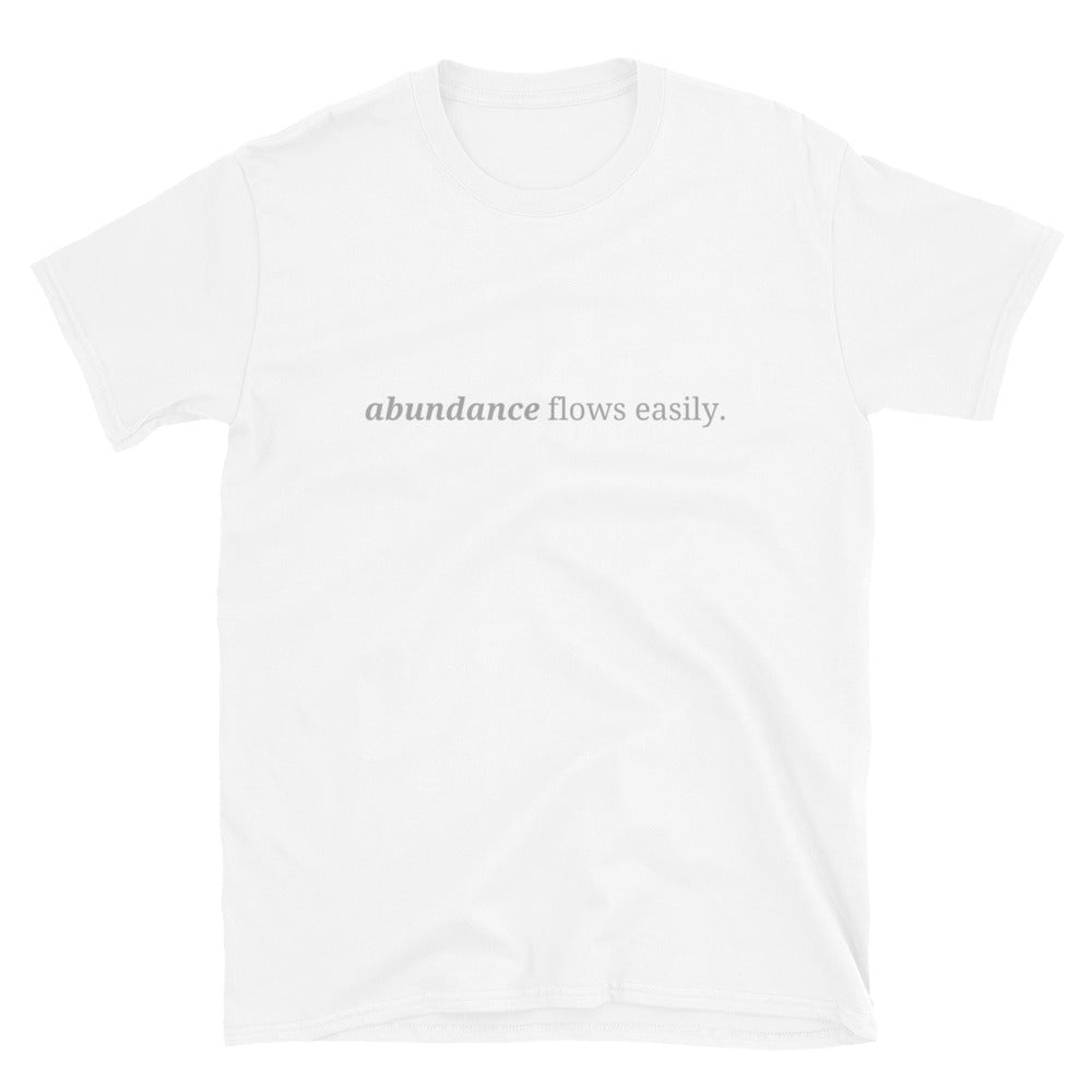 White t-shirt with the phrase "abundance flows easily." printed on the front, available in color options black, navy blue, gray, white, and light blue, available in sizes S to 3XL.