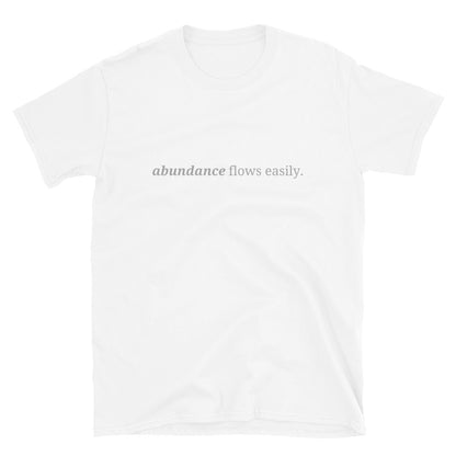 White t-shirt with the phrase "abundance flows easily." printed on the front, available in color options black, navy blue, gray, white, and light blue, available in sizes S to 3XL.