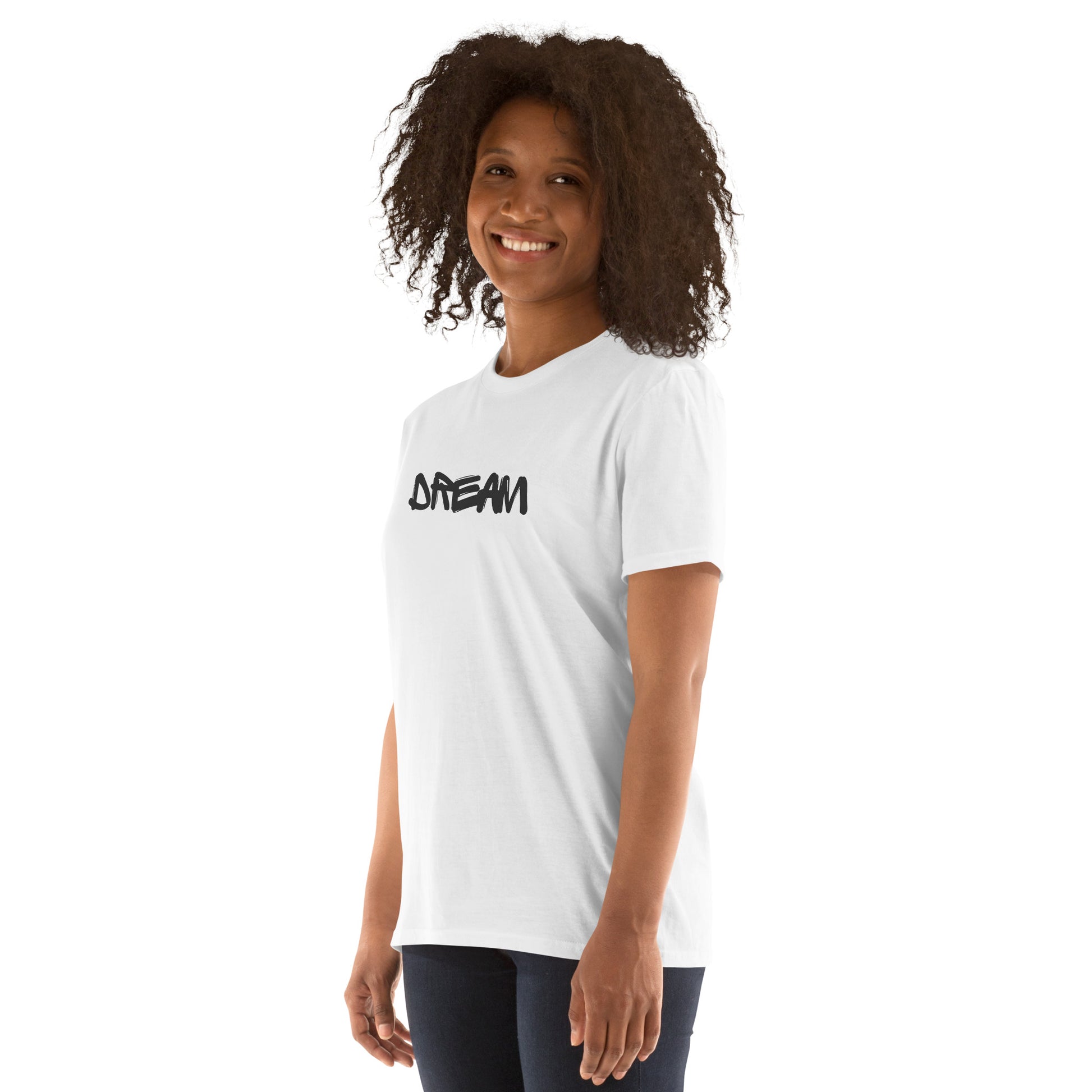 A woman with a joyful expression and curly hair is wearing a white t-shirt with the word "DREAM" in bold, stylized black letters, embodying a spirit of aspiration and inspiration.