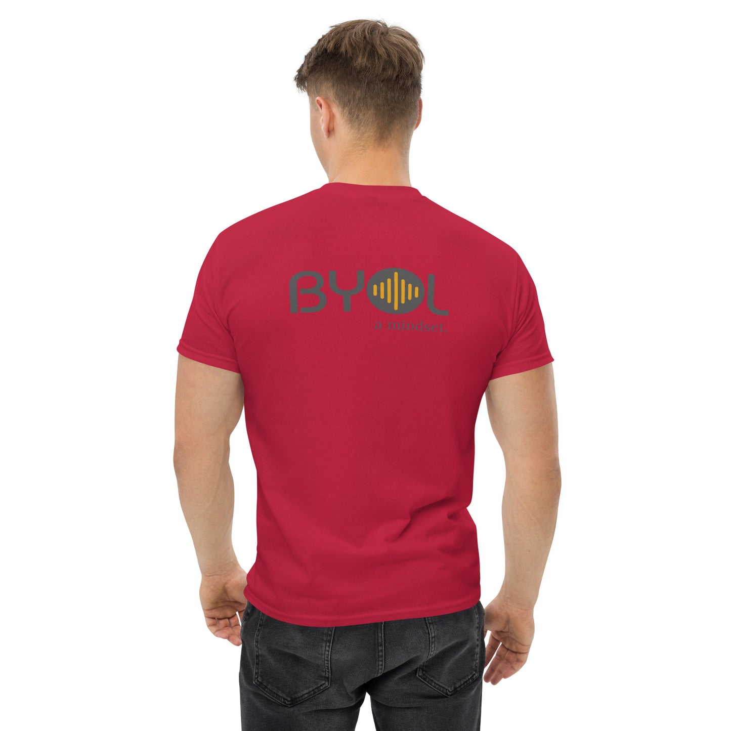 A young man with short blonde hair wearing a maroon "BYOL: a mindset" T-shirt, viewed from the back. The T-shirt features the "BYOL" logo in gray and yellow on the back and is available in multiple colors (maroon, black, brown, gold, plus more) and sizes (S-3XL). The "be you out loud" logo is displayed at the top.