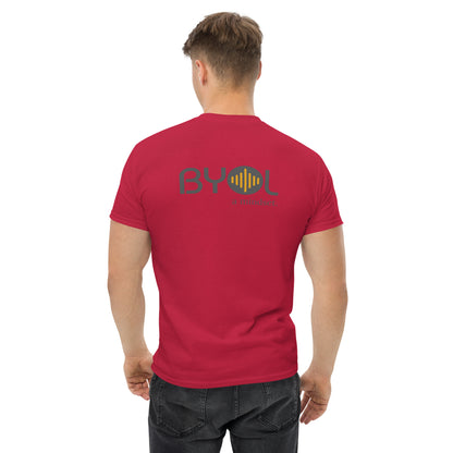 A young man with short blonde hair wearing a maroon "BYOL: a mindset" T-shirt, viewed from the back. The T-shirt features the "BYOL" logo in gray and yellow on the back and is available in multiple colors (maroon, black, brown, gold, plus more) and sizes (S-3XL). The "be you out loud" logo is displayed at the top.