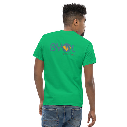 A young man with short hair wearing a green "BYOL: a mindset" T-shirt, viewed from the back. The T-shirt features the "BYOL" logo in teal and yellow on the back and is available in multiple colors (maroon, black, brown, gold, plus more) and sizes (S-3XL). The "be you out loud" logo is displayed at the top.